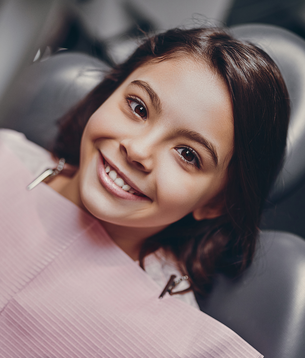 Smiling young girl in dental chair looking up