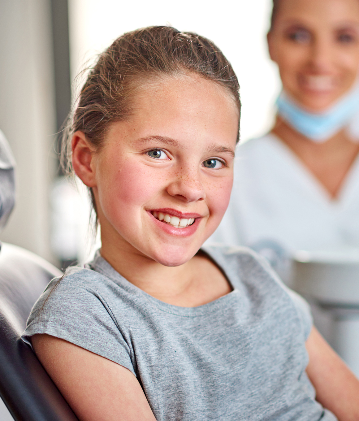 Child in gray tee shirt smiling in dental chair