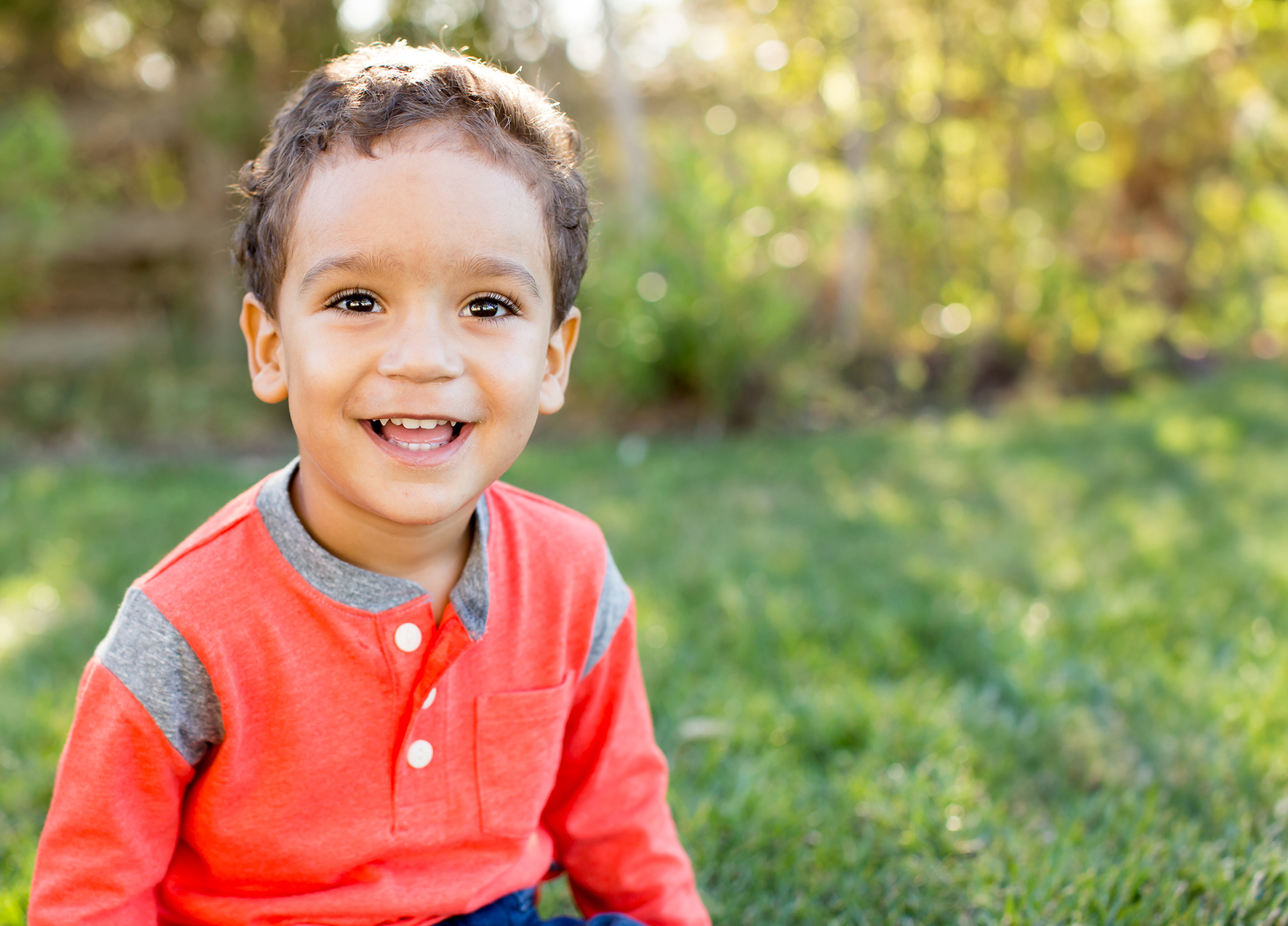 Young boy in orange shirt smiling after receiving pediatric dental services in Murphy