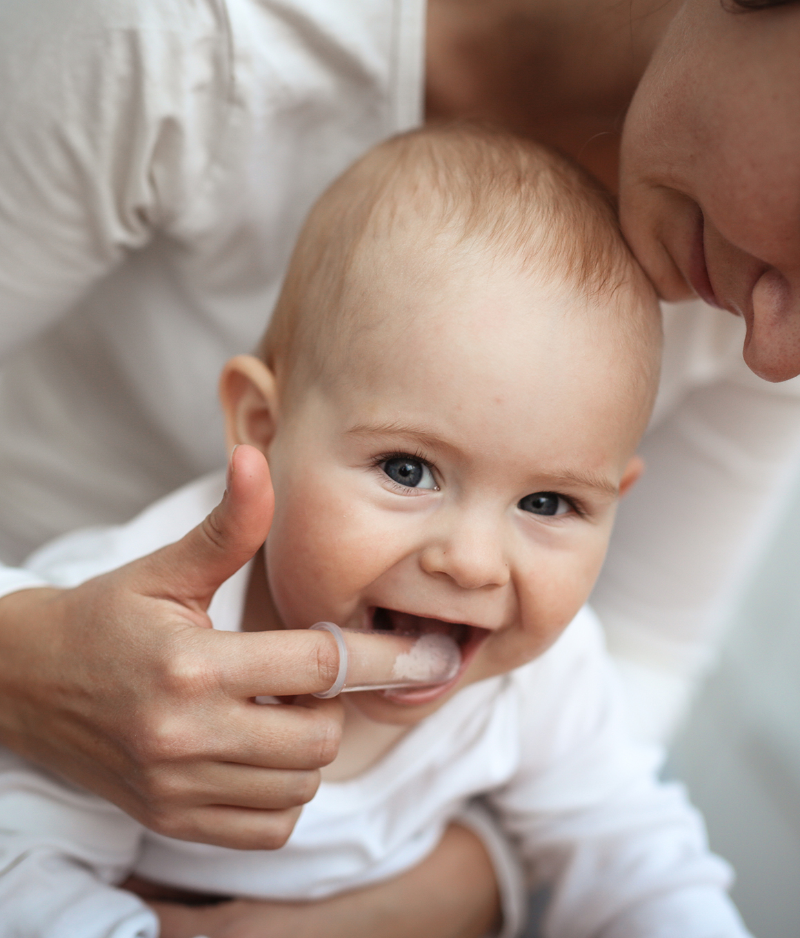 Parent with cover over their finger in their toddlers mouth