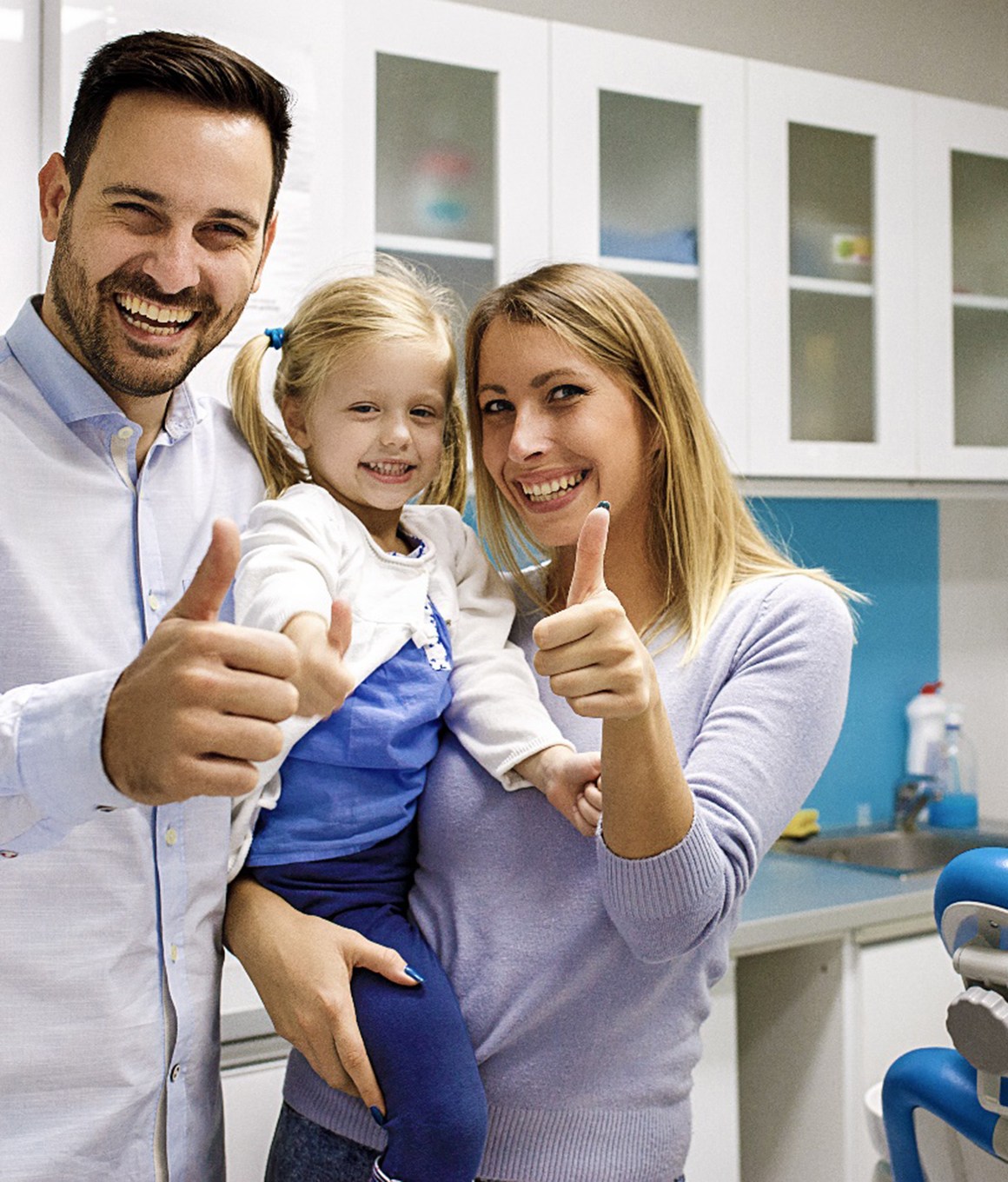 Mom, dad, and daughter giving thumbs up at dentist's office