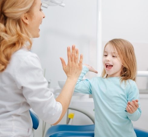 Young girl giving high five to dental team member