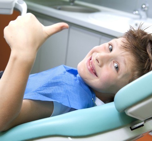 Boy giving thumbs up in dental chair