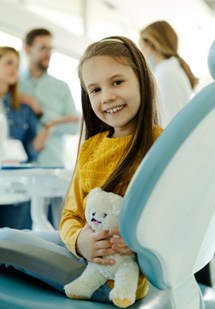 Child smiling while dentist and parents discuss treatment optionsl