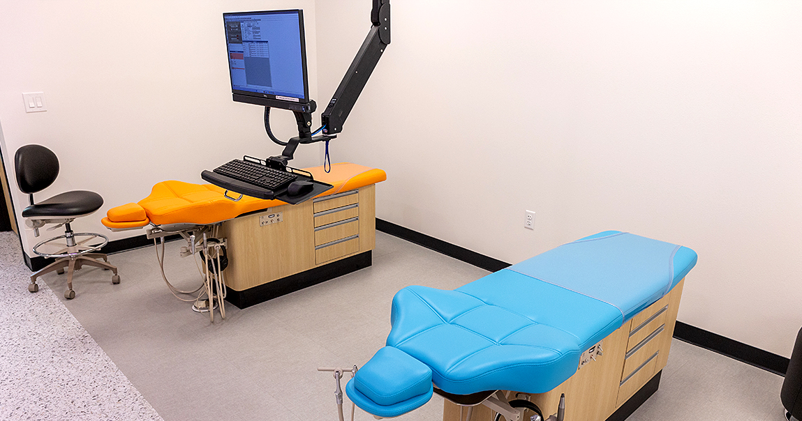 Two dental treatment chairs with computer monitor between them