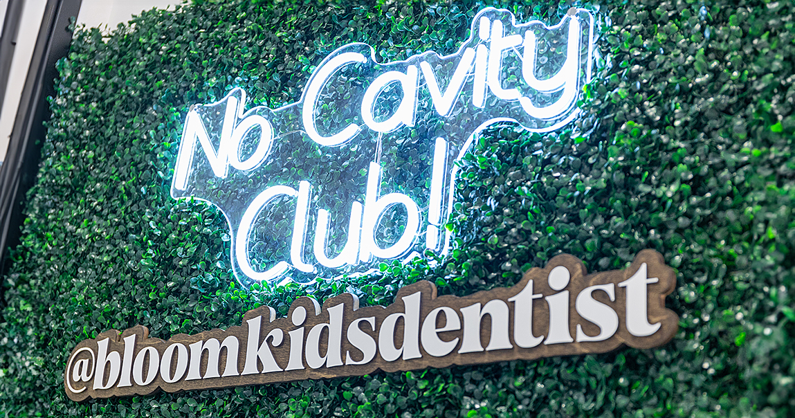 Neon sign that reads no cavity club followed by at bloomkidsdentist