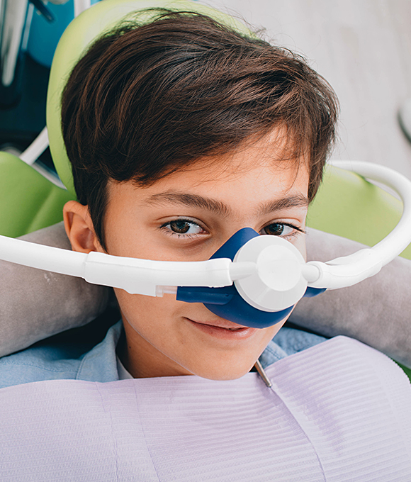 Boy in dental chair with nitrous oxide mask over his nose