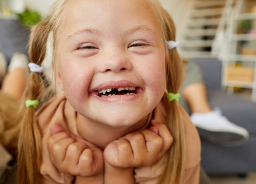 Girl with pigtails grinning after seeing pediatric special needs dentist in Murphy