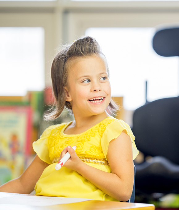 Girl sitting at desk and holding marker