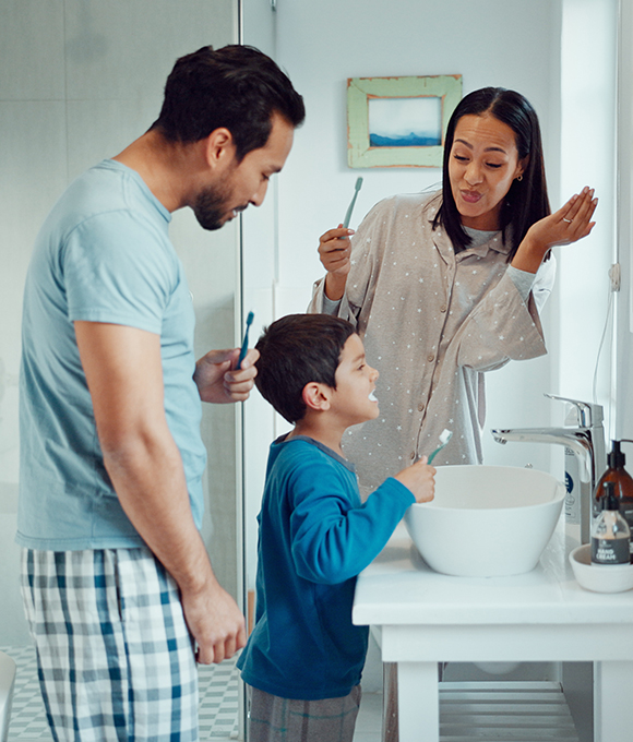 Parents and young son brushing their teeth together