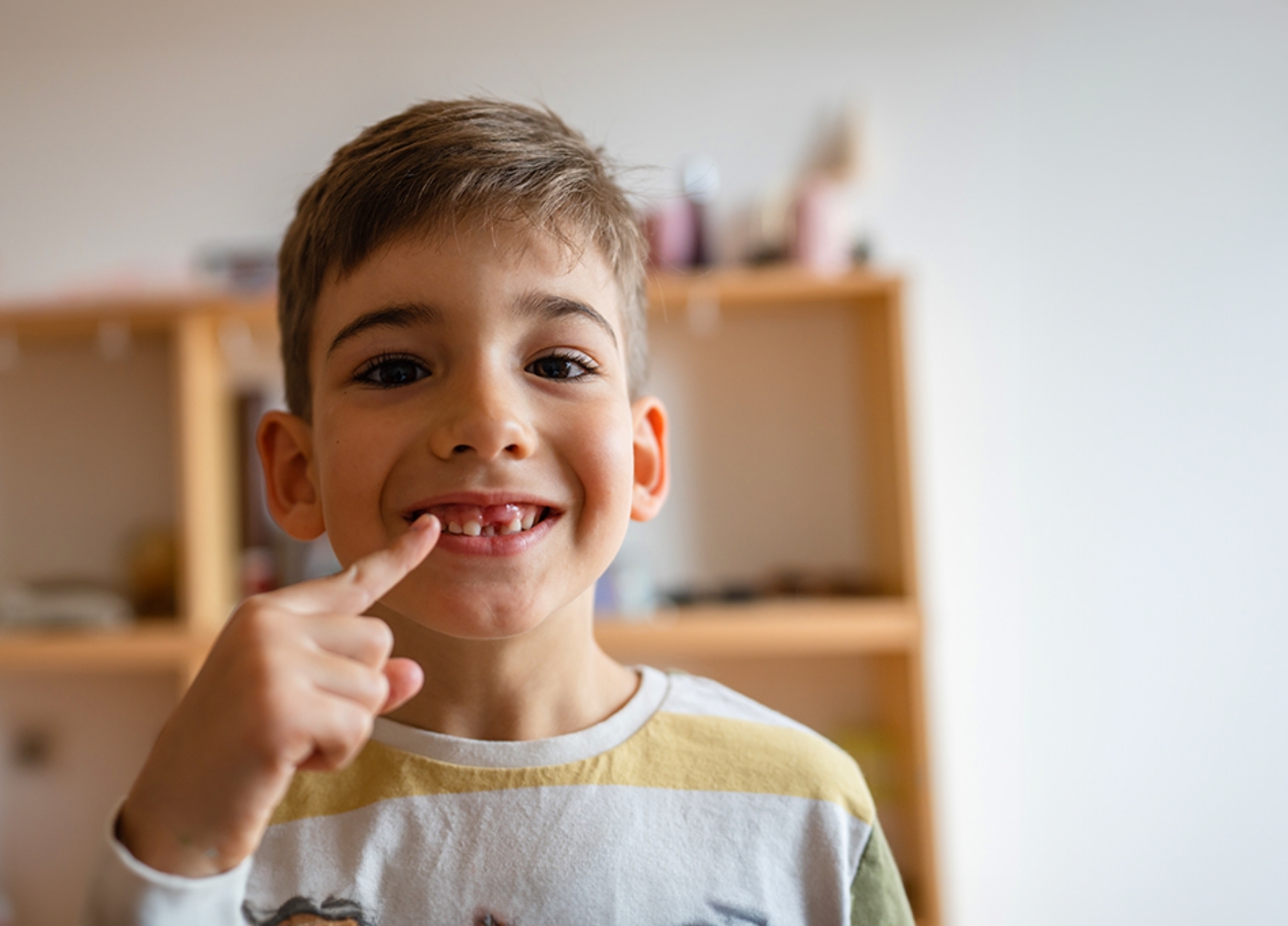 Boy pointing to his smile with a missing tooth after a tooth extraction in Murphy