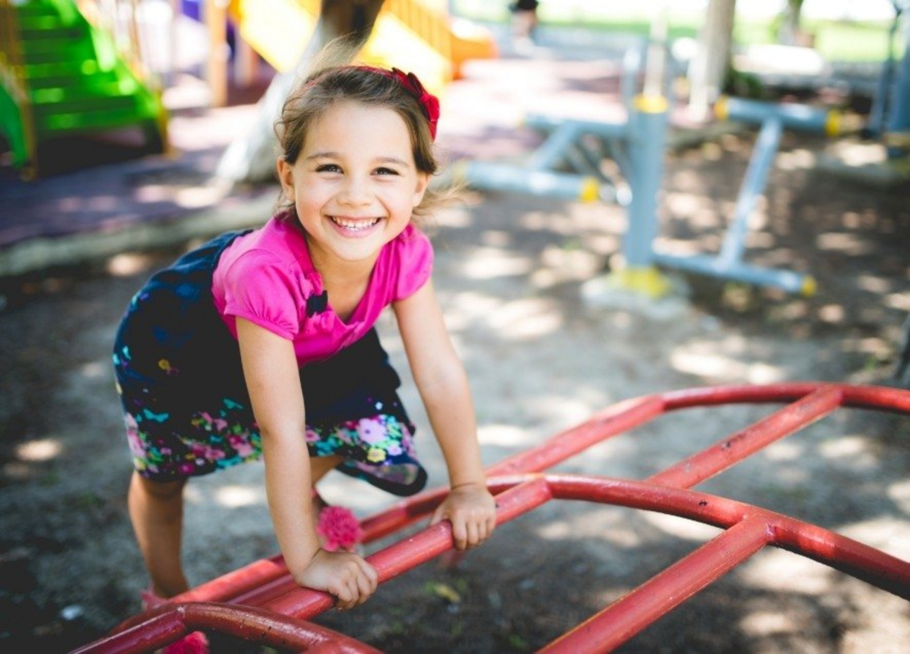 Girl smiling on outdoor jungle gym after seeing pediatric dentist in Murphy