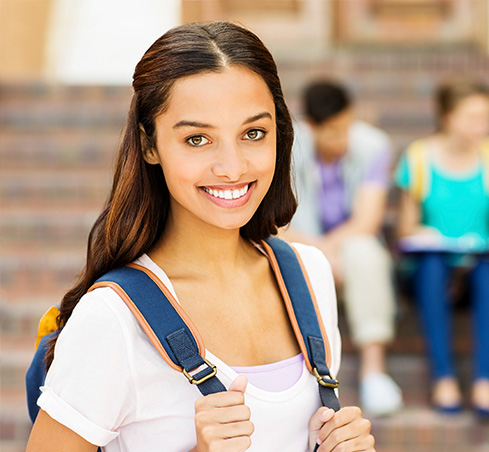 Teenage girl with backpack smiling in school hallway