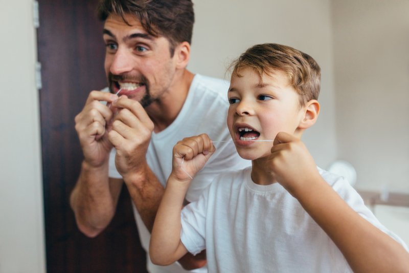 Parent and child brushing their teeth for dental health in a mirror