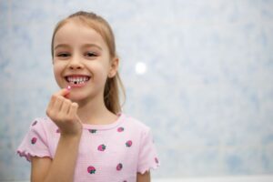 Happy little girl holding a lost baby tooth